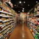Una vista representativa de auditoría de puntos de venta en un supermercado, con un pasillo bien surtido de góndolas y productos, ilustrando el proceso de evaluación y optimización de la disposición y calidad de los productos en el establecimiento.